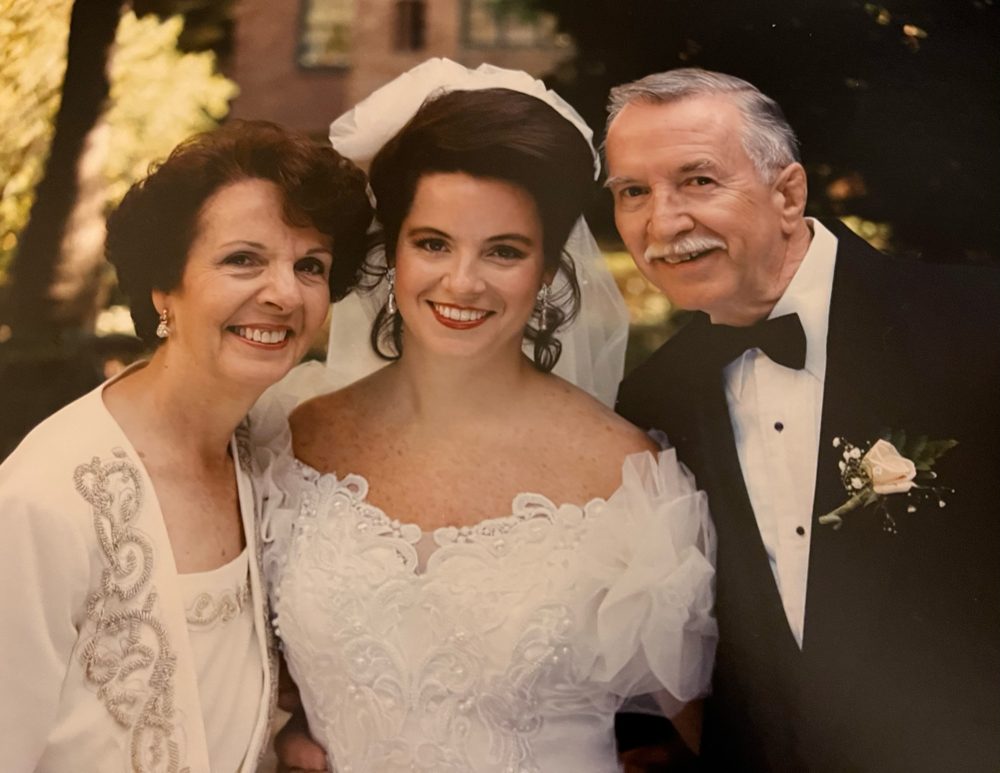 Diane in her wedding gown, smiling between her parents