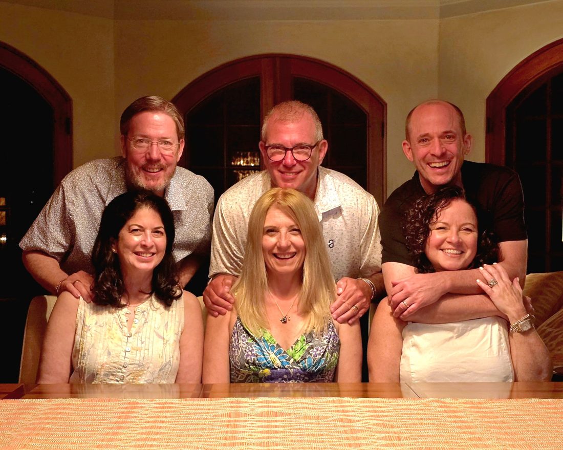 The same three couples, years later, in the same pose around a dining table