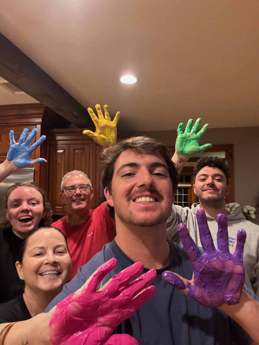 Diane with her family, everyone holding up paint-covered hands and laughing